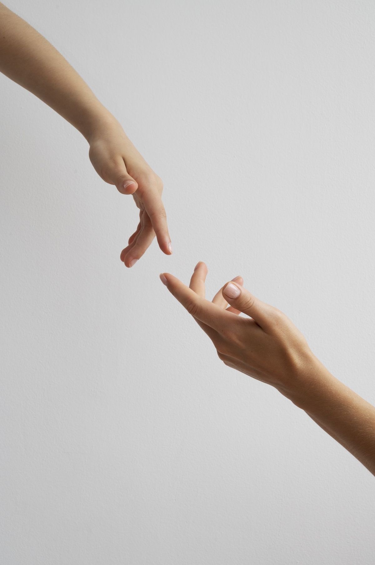 Divas rokas, kas stiepjas viena pretī otrai uz gaiša fona